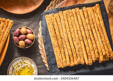 Delicious breadsticks grissini sticks with fresh herbs on top. Served with pickled olives and creamy dip with drops of olive oil and fresh thyme. - Powered by Shutterstock