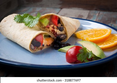 Delicious breakfast burrito stuffed with eggs, avocado, olives and chili peppers. Served with tomato and salad and a slice of freshly cut orange.