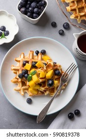 Delicious Breakfast With Homemade Waffles, Fresh Mango, Blueberries, Maple Syrup And Yogurt; Overhead Shot