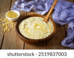 Delicious breakfast: millet porridge in a plate on a wooden table. Millet porridge with milk and butter.