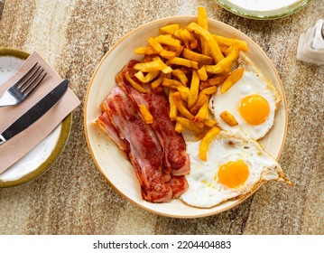 Desayuno delicioso - huevos revueltos con bacon y patatas fritas