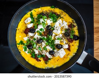 Delicious breakfast - scrambled eggs with feta cheese, sun-dried tomatoes and black olives served in frying pan 