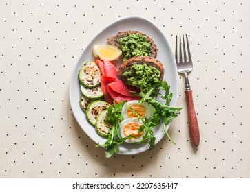 Delicious Breakfast, Snack - Boiled Egg, Smoked Salmon, Grilled Zucchini, Avocado Toast On A Light Background, Top View