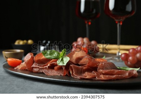 Delicious bresaola, tomato and basil leaves on grey textured table