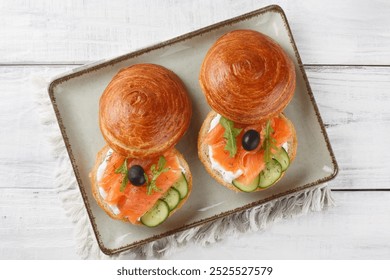 Delicious brioche sandwich with smoked salmon, cream cheese, cucumber and olives close-up on plate on table. Horizontal top view from above
 - Powered by Shutterstock