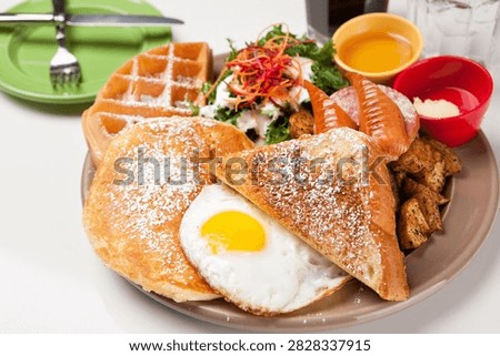 A delicious brunch sampler featuring toast, fried egg, waffle, sausage, and potatoes.