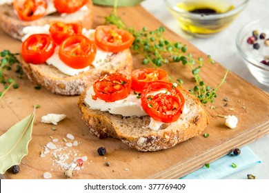 Delicious bruschetta with roasted tomatoes, feta cheese and herbs on wooden board - Powered by Shutterstock