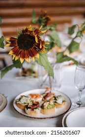 Delicious Bruschettas With Different Ingredients On A White Plate. Guacamole With Shrimp, Prosciutto, Salmon And Dorblu Cheese. Outdoor Feast On Holiday. Decor From Sunflower On Party