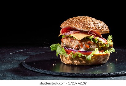 Delicious Burger With Cheese And Vegetables On The Dark Background