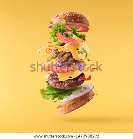 Delicious burger with flying ingredients isolated on yellow background. Food levitation concept. High resolution image