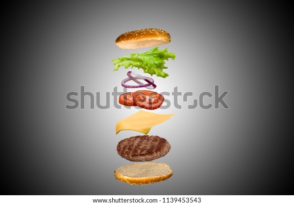 Delicious burger with flying ingredients\
isolated on gray gradient\
background.