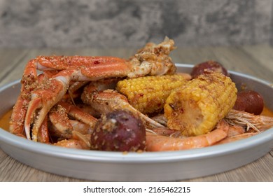 Delicious Buttery Plate Of Boiled Snow Crab Legs With Corn On The Cob And Sausage For A Tasty Seafood Meal.