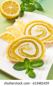 Delicious Cake Roll With Lemon Marmalade And Marshmallow. Sliced Rolls On A Plate, Lemon And Mint. Tasty Fruit Dessert. Vertical, Selective Focus