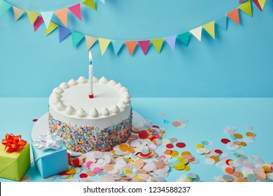 Gâteau délicieux avec des saupoudrées de sucre, des cadeaux et des confettis sur fond bleu avec saucisse colorée