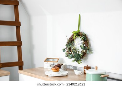 Delicious Cake, Utensils On Kitchen Counter And Easter Wreath Near White Wall