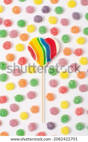 Delicious candy pattern with rainbow candy cane in the middle. Sugar candies in red, green, yellow, orange and purple. A modern concept of sweets. Lgbtq symbol.