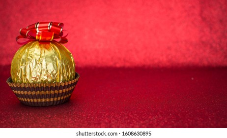 Delicious candy wrapped in gold foil on red background - Powered by Shutterstock