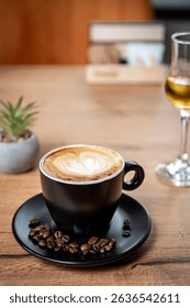 A delicious cappuccino with heart-shaped latte art, surrounded by rich coffee beans on a black saucer—perfectly capturing the essence of quality coffee.
