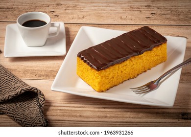 A Delicious Carrot Cake With Chocolate Icing And A Cup Of Coffee.