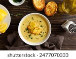 Delicious cauliflower cheese soup in white bowl over wooden background. Vegetarian or healthy diet food concept. Top view, flat lay