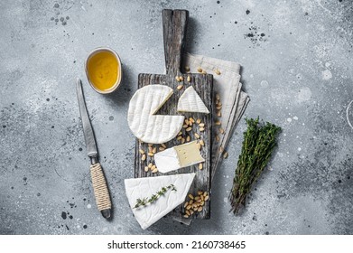 Delicious cheese brie and camembert on wooden board with herbs and nuts. Dairy French products. Gray background. Top view.