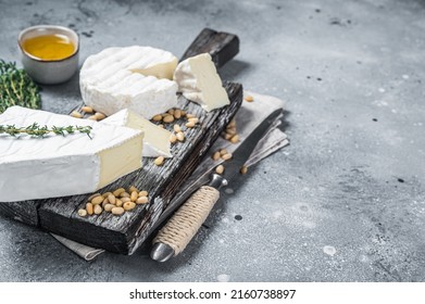 Delicious cheese brie and camembert on wooden board with herbs and nuts. Dairy French products. Gray background. Top view. Copy space. - Powered by Shutterstock