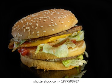 Delicious Cheeseburger With Beef Cutlet, Lettuce, Tomato Slices, Red Onion And Sesame Seed Bun. Cheeseburger On A Wooden Table Against A Dark Background. Close Up. Copy Space.