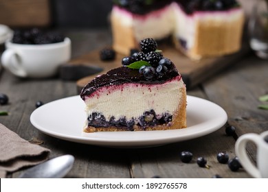 Delicious cheesecake with wild berries. Dessert with blueberries and blackberries. Whole fresh berries inside and blueberry jelly on top.