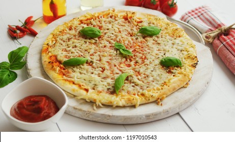 Delicious cheesy italian pizza served on white rustic wooden table with ingredients around. Shot from side.