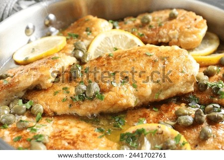 Delicious chicken piccata with herbs in pot, closeup