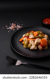 Delicious chicken slices and steamed vegetables carrots, broccoli, asparagus beans and peppers on a dark concrete background - Shutterstock ID 2282646555
