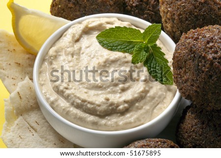Delicious chick-pea hummus with falafel balls and pita bread.  Garnished with mint and lemon. Stock photo © 