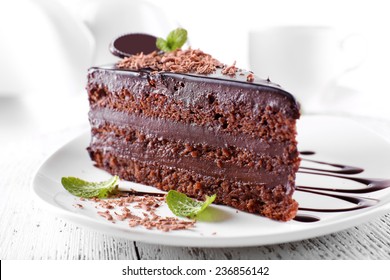 Delicious chocolate cake on plate on table on light background - Shutterstock ID 236856142