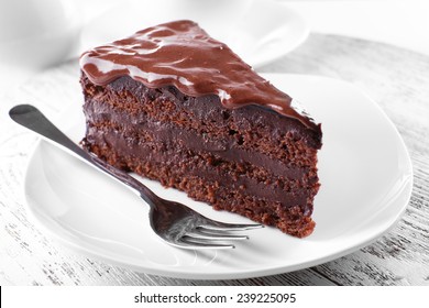 Delicious chocolate cake on plate on table on light background - Shutterstock ID 239225095