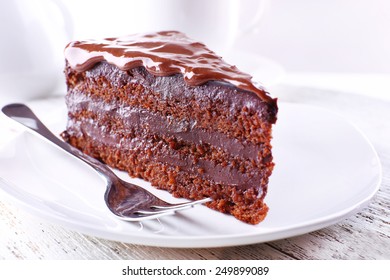 Delicious chocolate cake on plate on table on light background - Shutterstock ID 249899089
