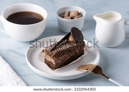 Delicious chocolate cake on plate and coffee on light table