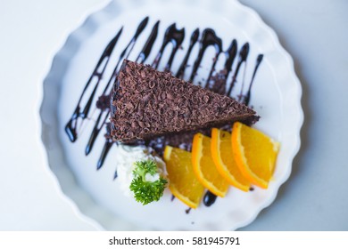 delicious chocolate cake on white plate with citrus, closeup.