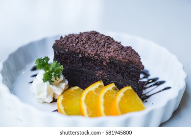 delicious chocolate cake on white plate with citrus, closeup.