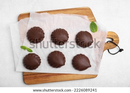 Delicious chocolate covered zephyrs and mint on white table, flat lay