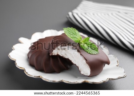 Delicious chocolate covered zephyrs with mint on black table, closeup