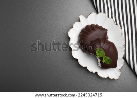 Delicious chocolate covered zephyrs with mint on black table, top view. Space for text