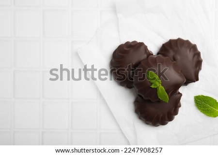 Delicious chocolate covered zephyrs with mint on white table, flat lay. Space for text
