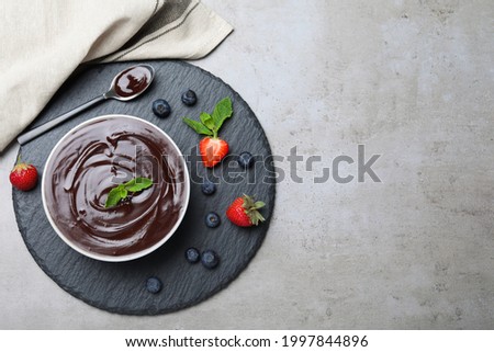 Delicious chocolate cream with berries and mint on grey table, top view. Space for text