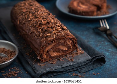 delicious chocolate roulade cake with chocolate cream, dark blue background. selective focus - Shutterstock ID 1639623451