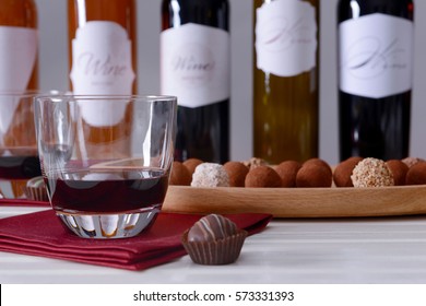 Delicious chocolate sweets and wine bottles on table