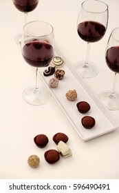 Delicious chocolates and glasses of wine on white table