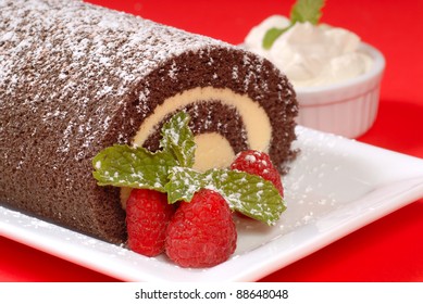 Delicious Christmas Buche de Noel cake with raspberries, whipped cream and powdered sugar