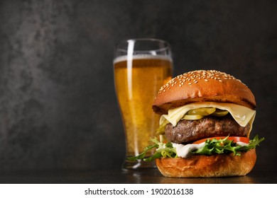 Delicious classic burger with cutlet and glass of cold beer on a stone background. Harmful and fast food. - Powered by Shutterstock