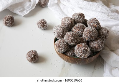 Delicious Coconut-Chocolate balls covered with grated coconut served in a coconut plate against white background. Copy space. Christmas, Indian burfi treat, healthy energising cookie concept

