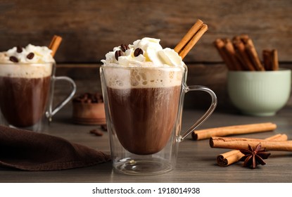 Delicious coffee with whipped cream and cinnamon on wooden table